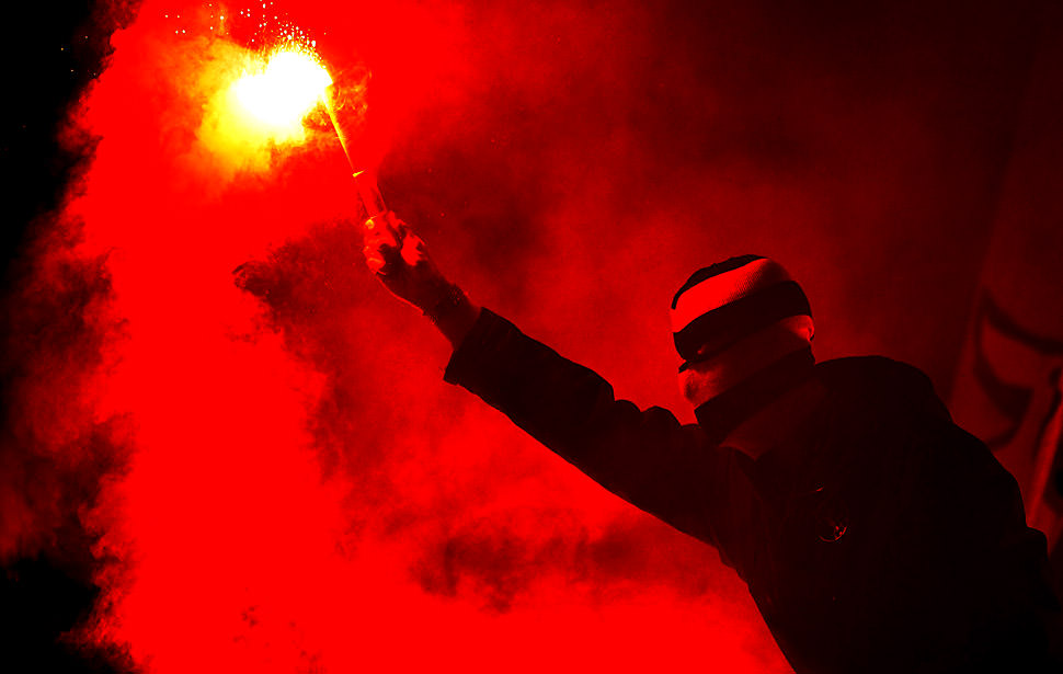 Football Politics: A supporters of Young Boys of Bern lights a flare during during a Champions League Group Play-off first leg football match against Tottenham Hotspur on August 17, 2010, at the Stade de Suisse, in Bern. TOPSHOTS/AFP PHOTO/FABRICE COFFRINI (Photo credit should read FABRICE COFFRINI/AFP/Getty Images)